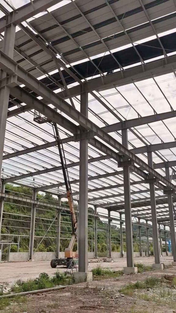 Montaje de una bodega de acero asequible utilizando una plataforma elevadora para fijar vigas de techumbre.