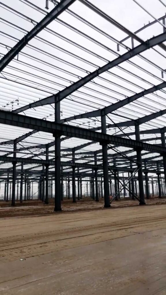 American standard steel building interior under construction with high-bay H-beam columns and clear-span portal frame design.