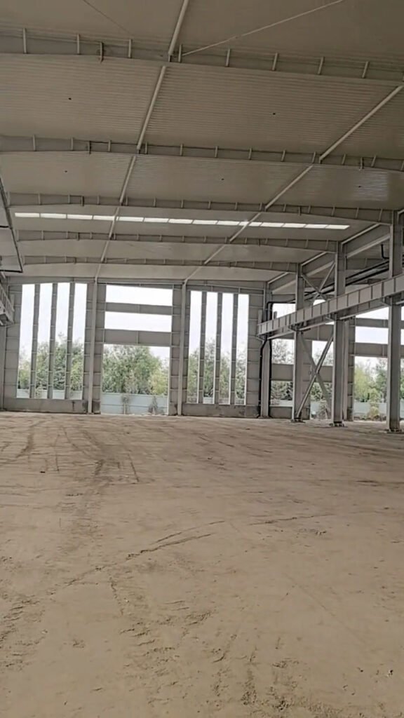 Interior despejado de una bodega de acero industrial con columnas alineadas y piso compactado listo para radier.
