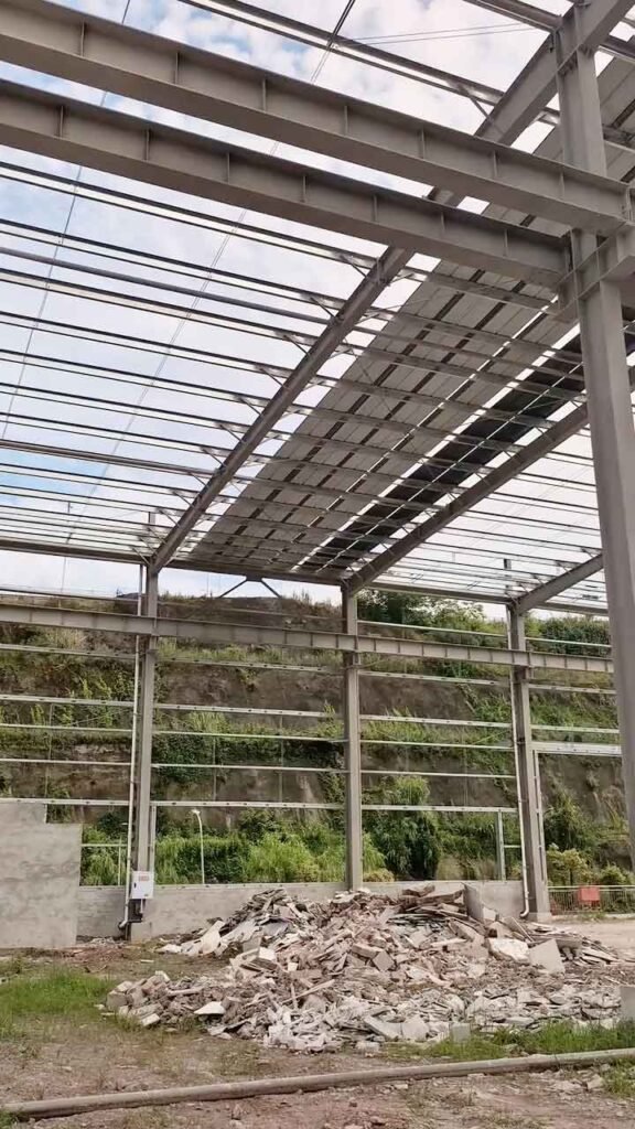Estructura de acero para una bodega económica en Perú con vigas H y paneles de techo parcialmente instalados.