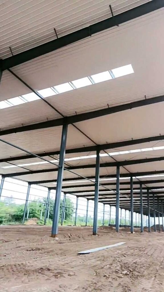 Long interior view of a coastal steel building highlighting the skylights and the anti-rust treatment on the rafters.