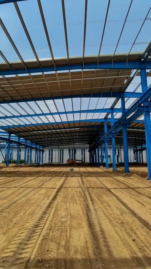 Interior de un distribution center warehouse en fase de nivelación de suelo y montaje de techumbre metálica.