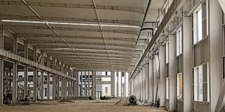 Vista interior de un edificio de bodega personalizado de gran luz con estructura de acero blanca y sistema de iluminación natural.