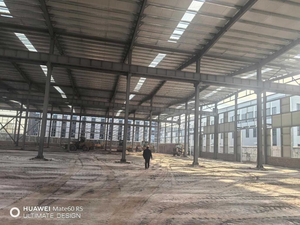 Interior de un almacén metálico de gran luz con tragaluces y sistema de aislamiento térmico en la techumbre.