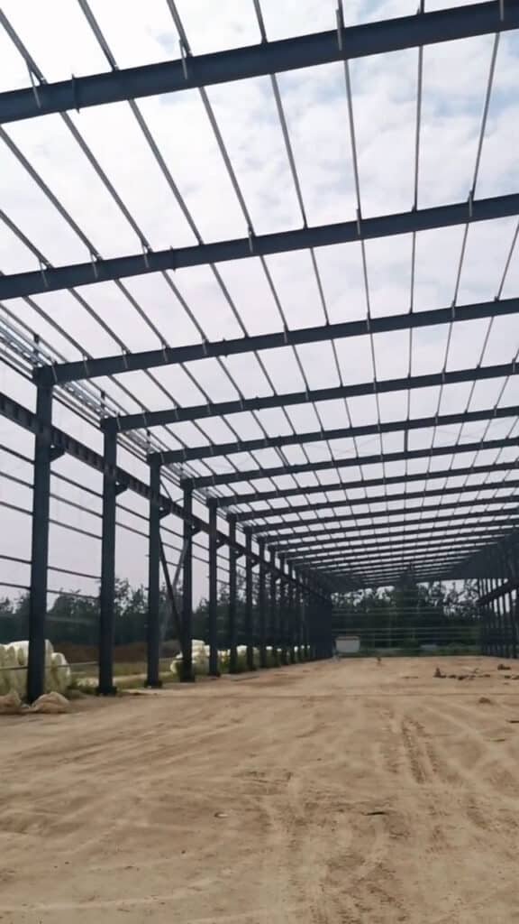 Detalle de una estructura metálica industrial de gran altura con entramado de correas tipo C para soporte de fachadas.