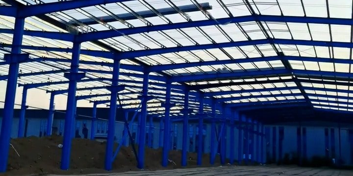 Industrial engineering services for large-span steel warehouses featuring blue anti-corrosive H-beam frames and translucent skylights.
