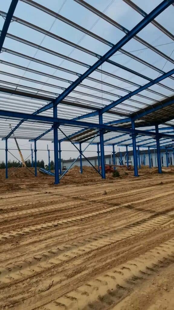 Panorámica de un industrial logistics building con cerchas de techo y preparación para pavimentación industrial de alta resistencia.