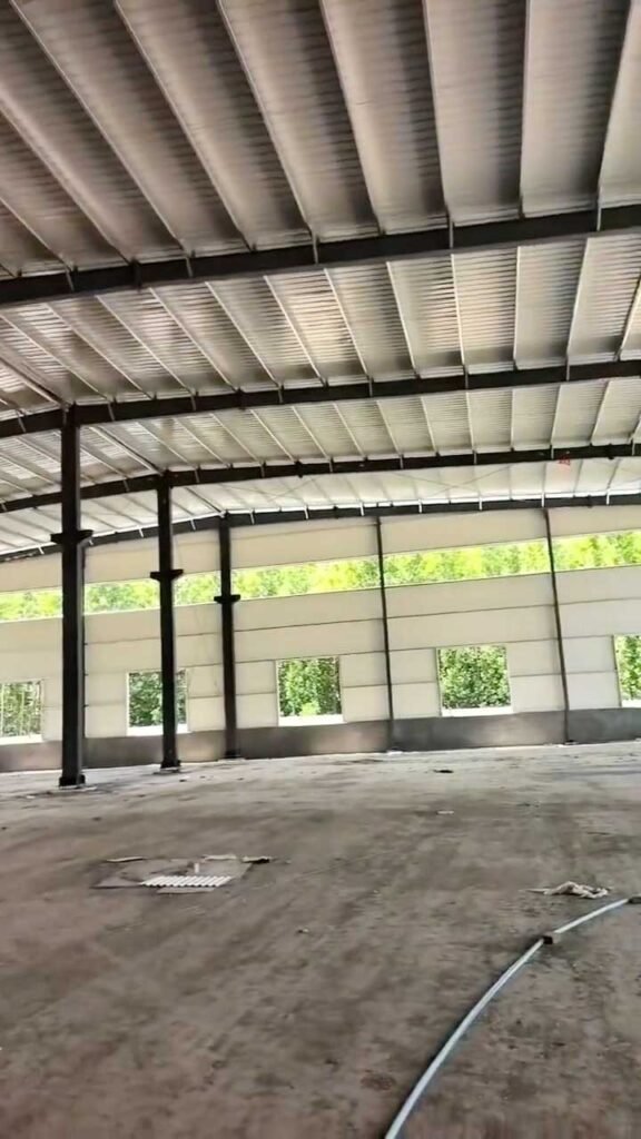 Interior de un industrial steel building masivo con suelo compactado y múltiples bahías de almacenamiento alineadas