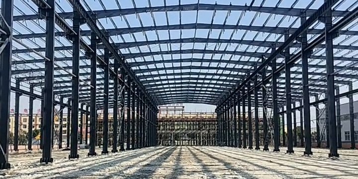 Panoramic view of a massive industrial steel frame spanning a wide area, showing the depth of the clear-span architecture.