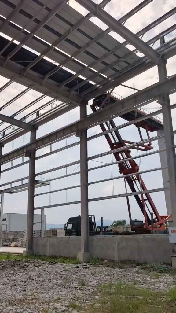 Columnas de acero reforzado y maquinaria de elevación en la obra de un edificio de almacenamiento industrial.