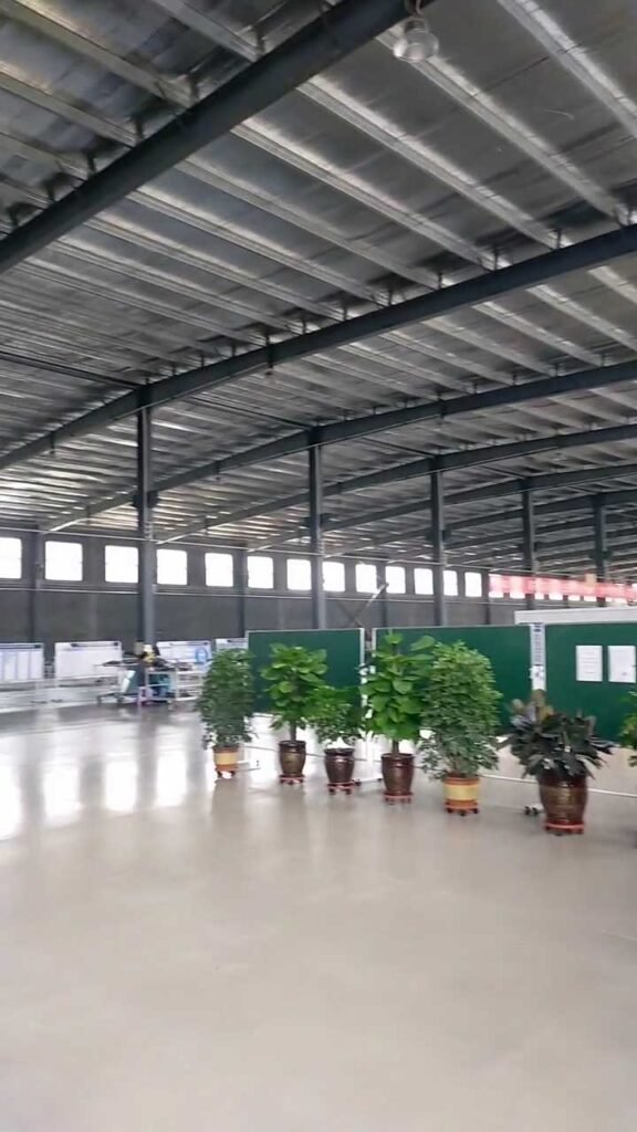 View inside a large span warehouse showing a professional industrial environment with potted plants and skylight illumination.