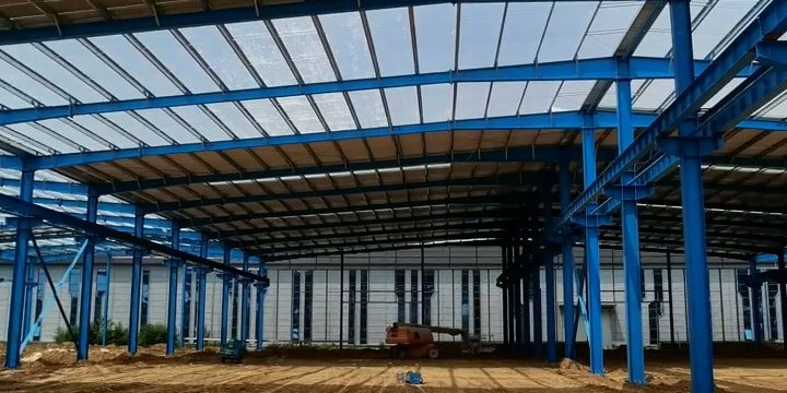 Construcción de un logistics warehouse building en Panamá con estructura de acero azul de gran luz y maquinaria de elevación.