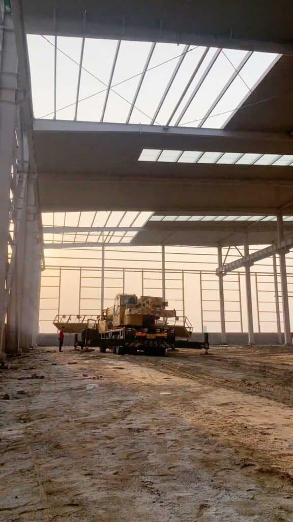 Construction site of a low-cost warehouse during sunset with a mobile crane preparing for the next phase of assembly.