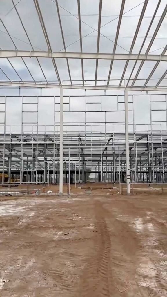 Perfiles de acero y vigas de un modular steel building depositados en el suelo de una obra de gran escala.