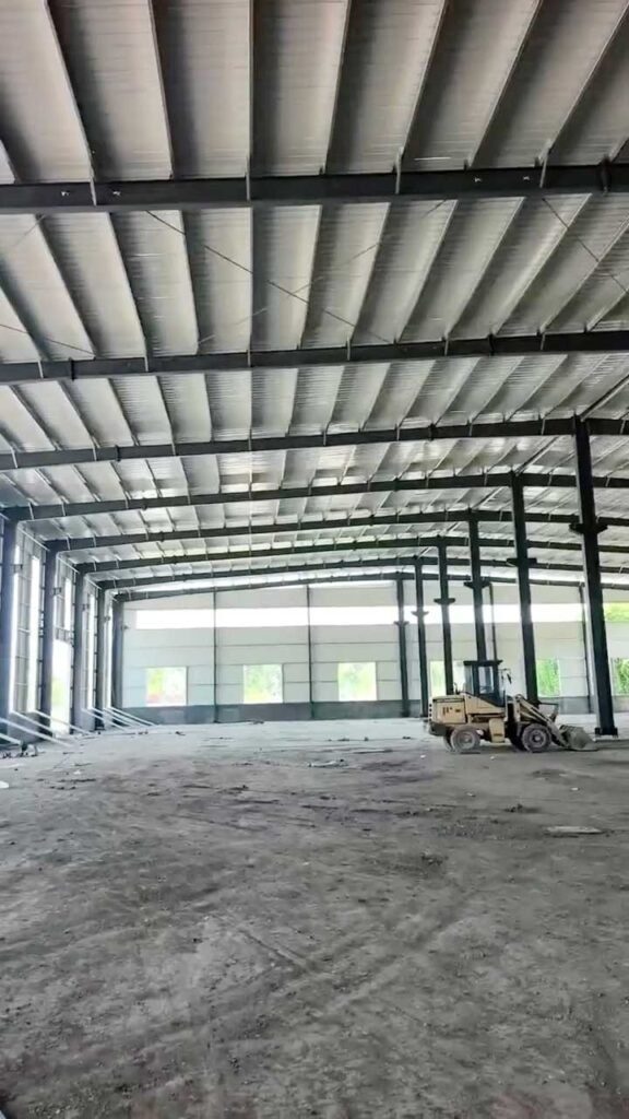 Interior de un PEB warehouse de gran luz con techumbre blanca aislante y vigas de acero de alta resistencia.