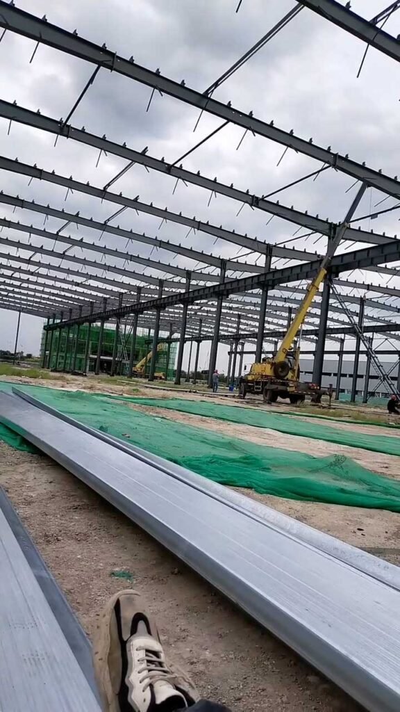 Mobile crane lifting steel trusses into place for a prefabricated industrial building assembly in a new industrial park.