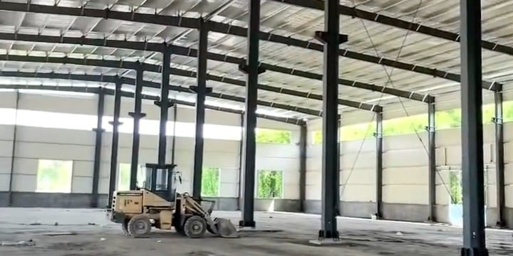 Vista panorámica completa de un prefabricated steel building en etapa de montaje estructural y cerramientos laterales.