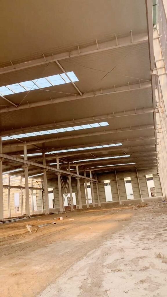 Perspective view of a massive prefabricated warehouse interior with multiple rows of natural lighting skylights.