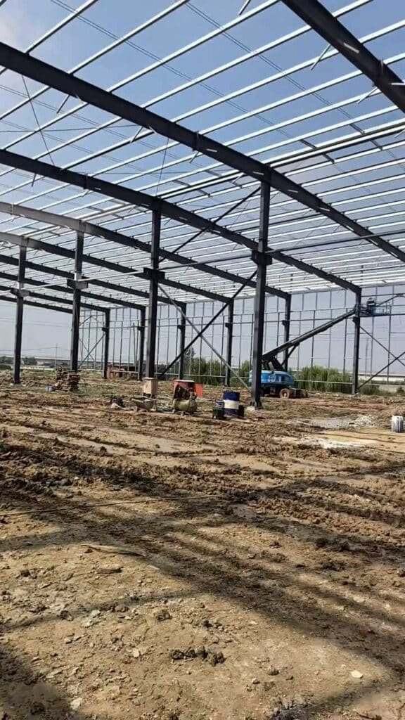 Perspectiva lateral de un prefabricated warehouse mostrando la alineación de pórticos y la preparación del radier
