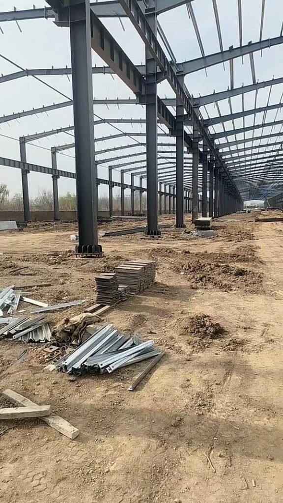 Close-up of steel columns and stacked materials at a prefabricated warehouse site ready for final assembly.