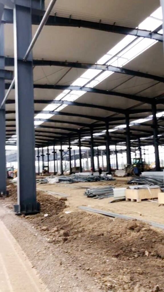Close-up of a high-quality steel construction site featuring precision-engineered base plates and partially installed roof sheeting