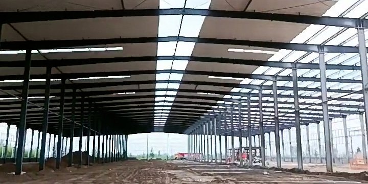 Wide clear-span interior of a massive warehouse showing the rust protection system applied to the purlins and main frames.