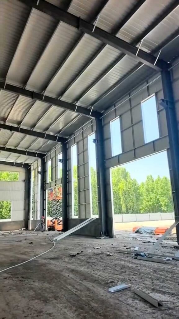 Detalle técnico de la techumbre de un steel frame building resaltando la unión de vigas de alma llena y lucernarios.