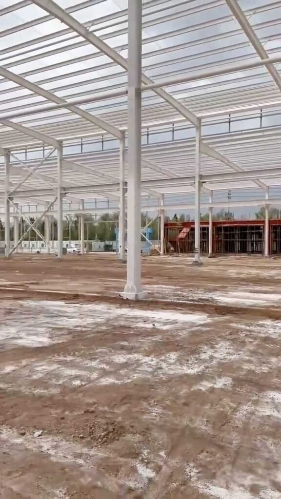 Detalle técnico de la techumbre de un steel frame building resaltando la unión de vigas de alma llena y lucernarios.
