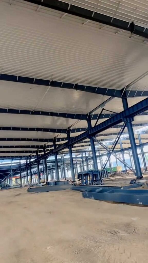 Estructura de marco de acero para almacén de gran altura con vigas de alma llena y cielo falso blanco aislante.
