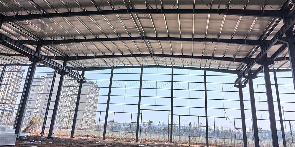 Interior de una nave industrial con techumbre de acero, sistema de aislamiento térmico de aluminio y vistas a zona urbana
