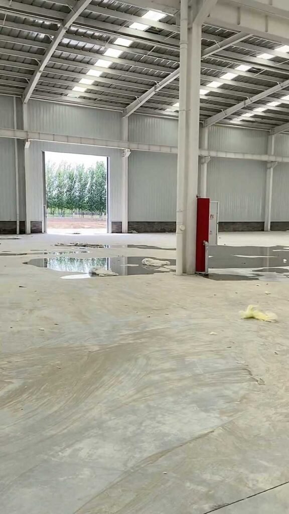 Piso industrial de concreto en preparación dentro de una estructura de bodega prefabricada en Bogotá.