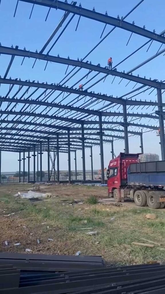 Workers performing roof assembly on a large-scale portal frame warehouse to determine sqm construction costs.