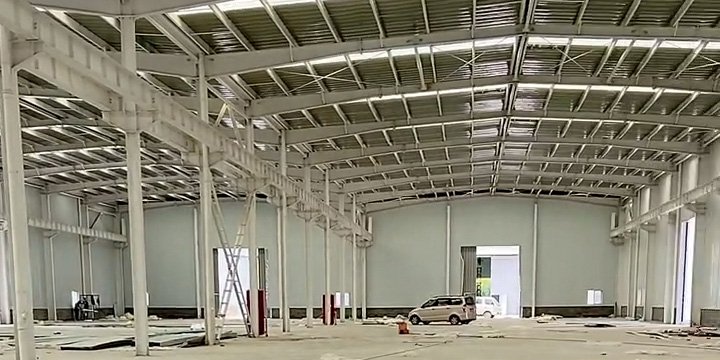 Vista interior de una bodega industrial de gran luz en Colombia con estructura de acero blanca y tragaluces.