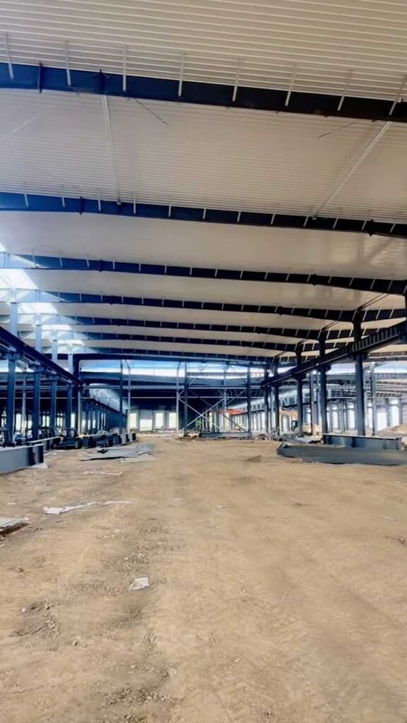 Interior de una warehouse steel structure de gran luz con techumbre blanca aislante y vigas de carga pesada.