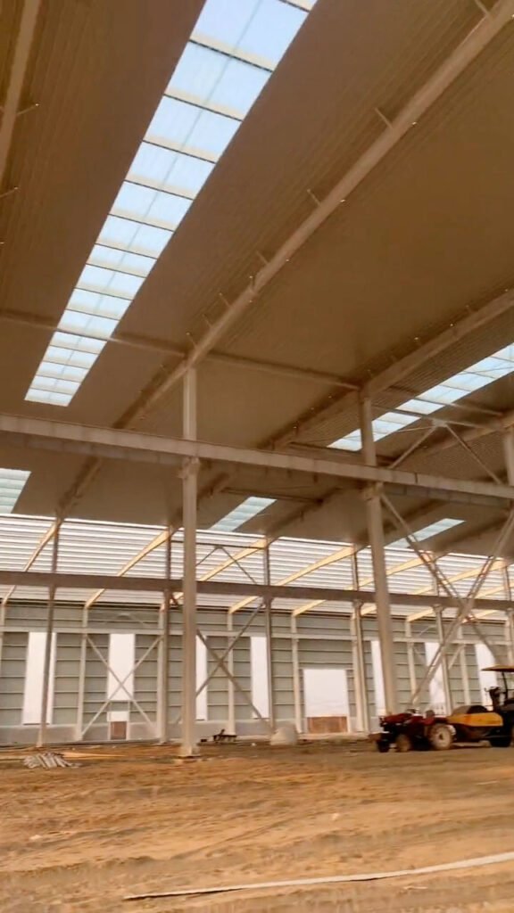 Heavy-duty warehouse steel structure frame with onsite tractor preparing the dirt floor for concrete pouring.