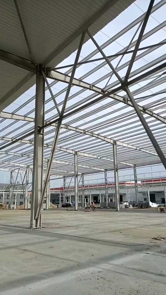 Clean interior view of a wide-span facility manufactured by our bulk steel structure supplier, featuring robust Q355 steel columns and heavy-duty roof framing.