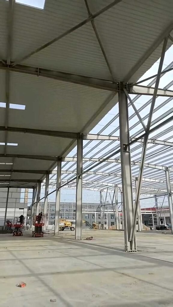 Massive clear-span warehouse interior showing standardized portal frames, highlighting the immense production capacity of our bulk warehouse supplier facility.