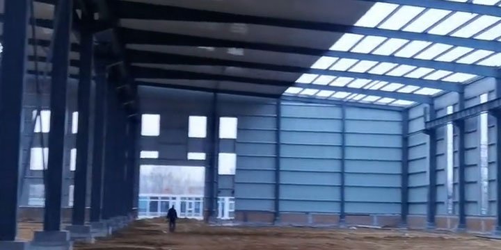 Perspectiva interior de estructuras metálicas para almacenamiento destacando la iluminación natural mediante tragaluces y ventanas.