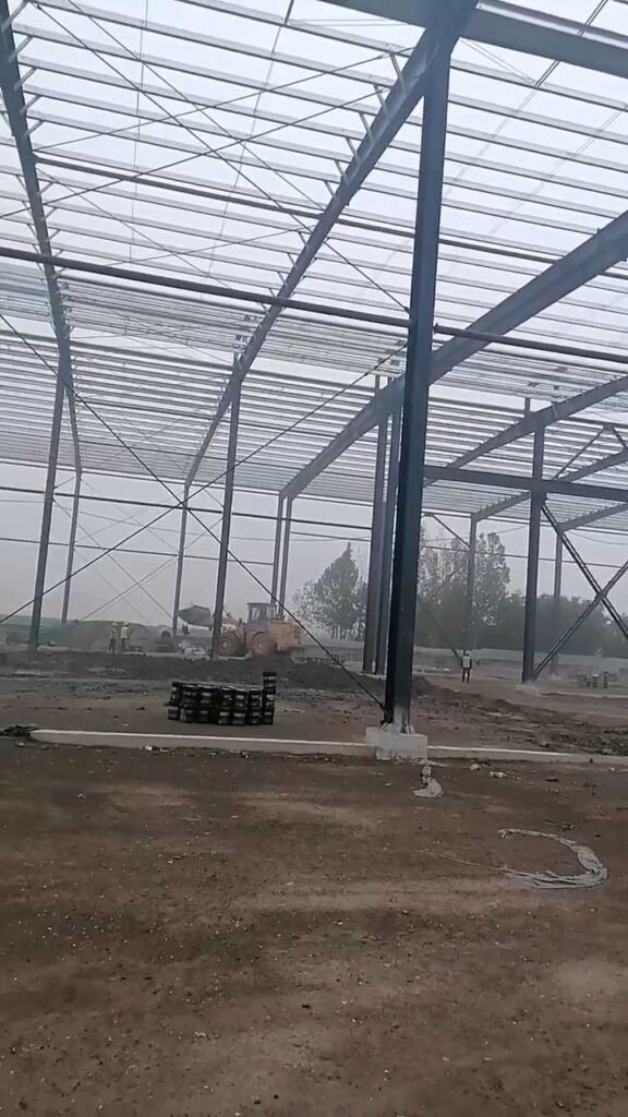 Earthmoving equipment preparing the interior ground of a PEB structure, showing how initial civil foundation works are a critical component of the total industrial steel building cost.