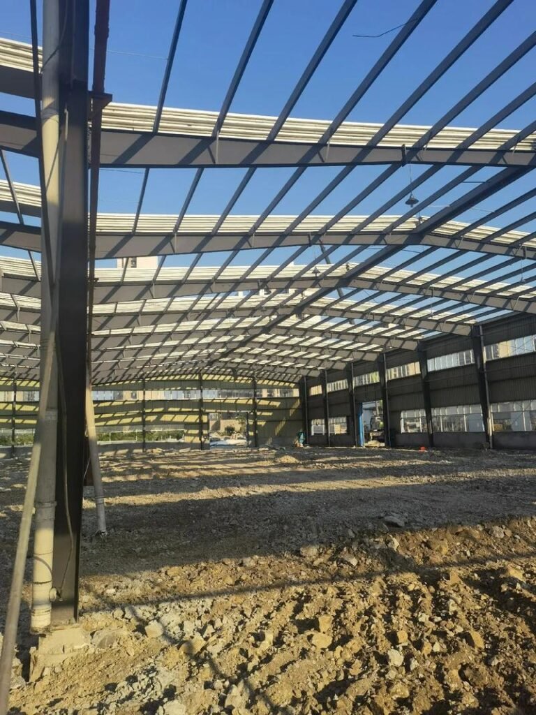 Wide interior view of a heavy-duty clear-span portal frame manufactured by a top industrial steel building supplier, featuring rigid columns and roof beams.