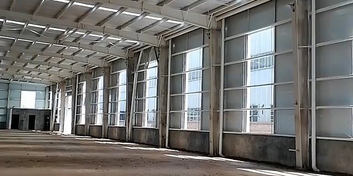 Interior side-wall view showing concrete dwarf walls, steel columns, and translucent lighting panels, which are strategic design choices that impact the overall industrial warehouse cost.
