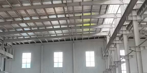 A yellow Komatsu excavator performing interior ground leveling and foundation preparation inside a large-scale pre engineered building.