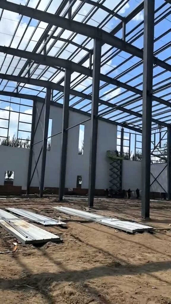 Construction teams on a scissor lift assembling heavy-duty columns, demonstrating the seamless on-site assembly designed for a prefabricated steel building distributor.