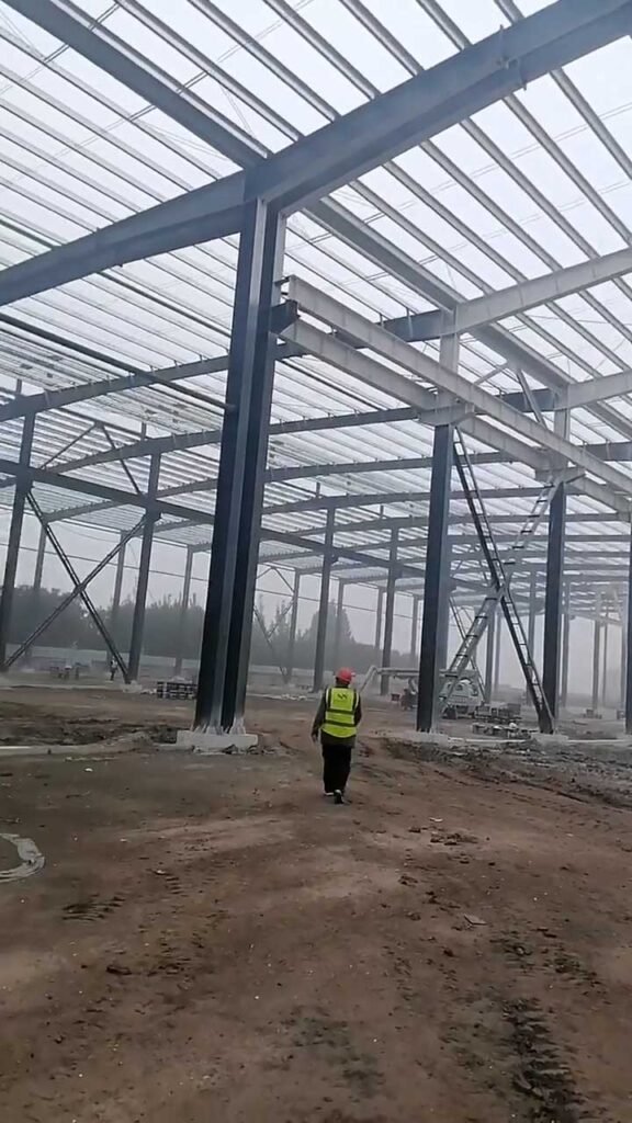An engineer walking through a multi-span steel structure, an efficient architectural choice that evenly distributes weight and lowers the total prefabricated steel building price.