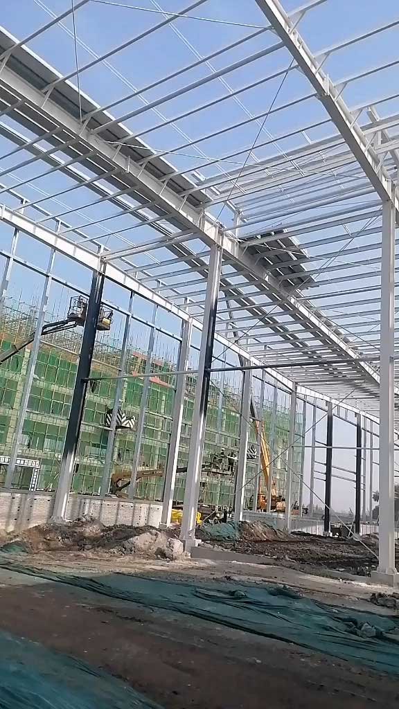 Workers using aerial lifts to install prefabricated roof rafters, highlighting the rapid assembly engineered by a global prefabricated steel building supplier.