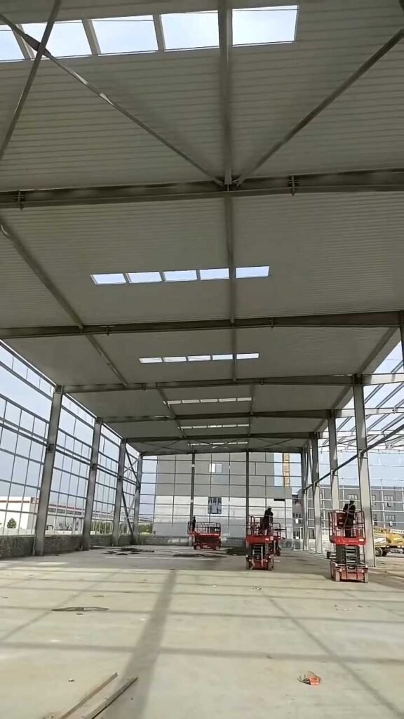 Construction teams on scissor lifts installing roof panels and securing high-strength bolts, demonstrating the seamless on-site assembly provided by a premium project steel structure supplier.