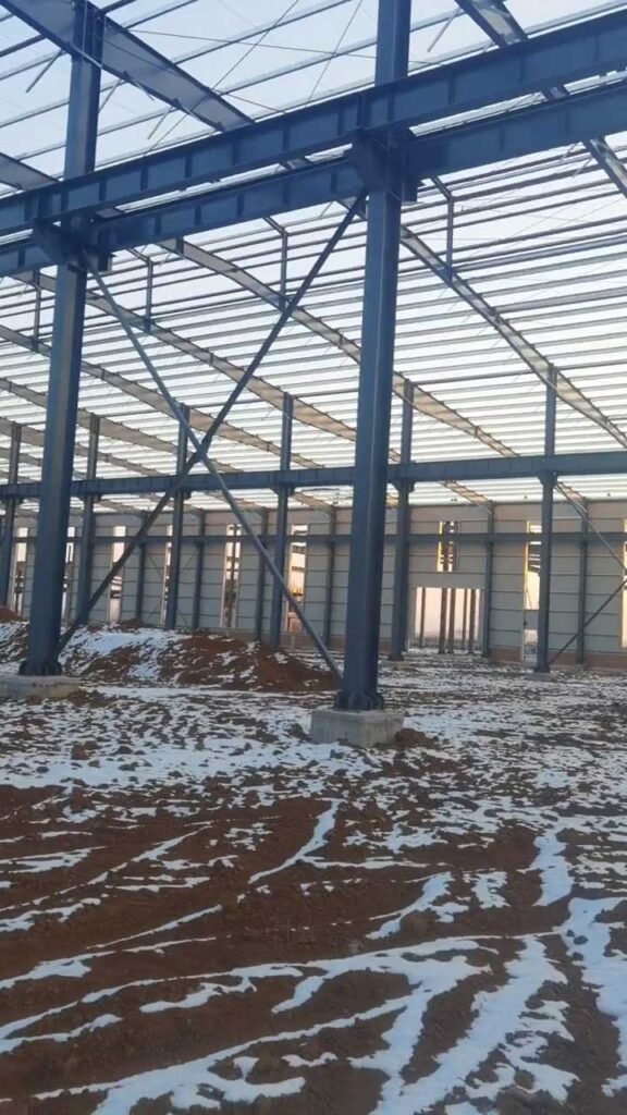 Installation of galvanized roof purlins and steel trusses on a prefabricated warehouse building designed for high snow loads.