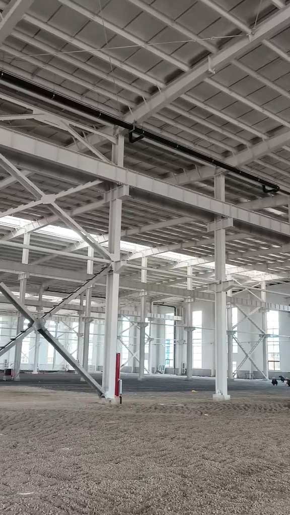Detailed view of a steel structure building ceiling featuring foil-faced thermal roof insulation, galvanized purlins, and rigid structural cross-bracing.