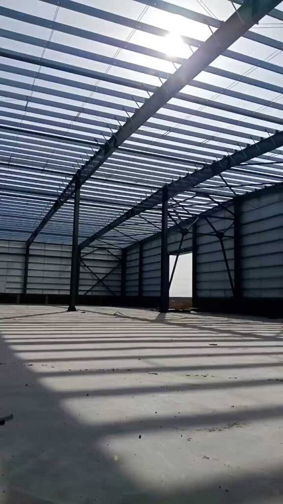 View of primary portal frame rafters and galvanized roof purlins engineered by a certified warehouse building import supplier.