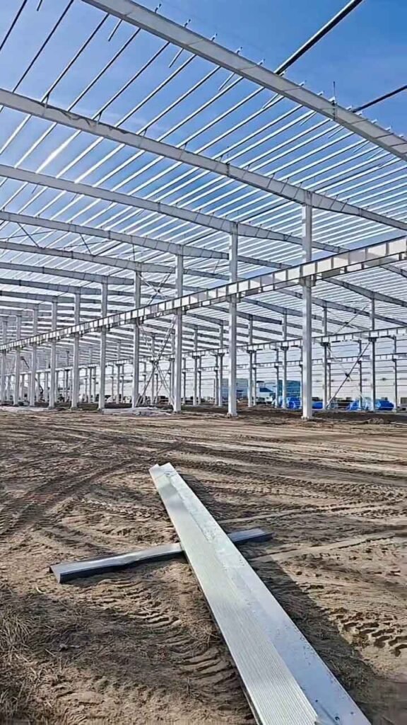 Ensamblaje en terreno de vigas y pórticos principales para un almacén con estructura metálica prefabricada.